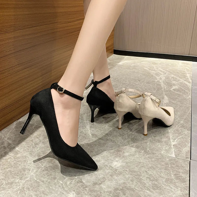 Women's black stiletto pump shoe with a decorative buckle and skull pattern on the toe.
