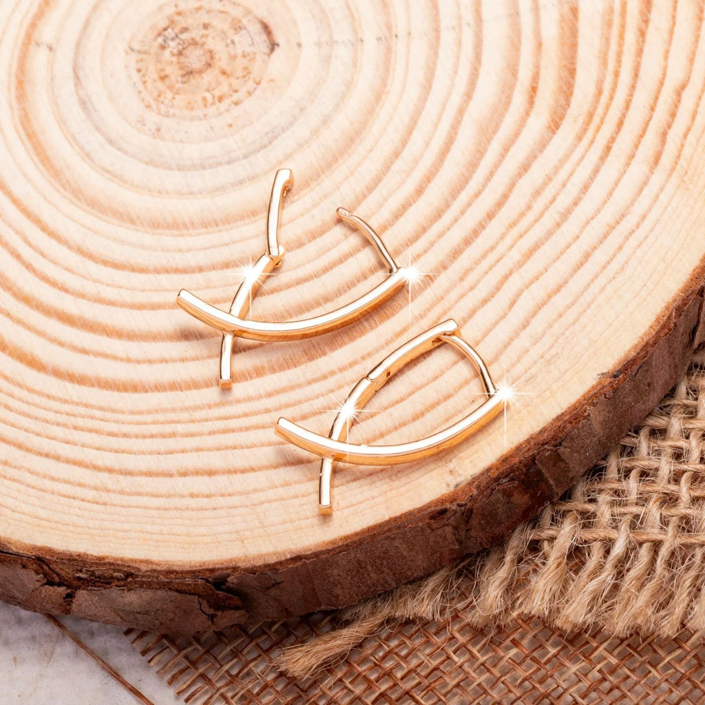 Rose gold cross shaped fashion earrings made from copper on a white background