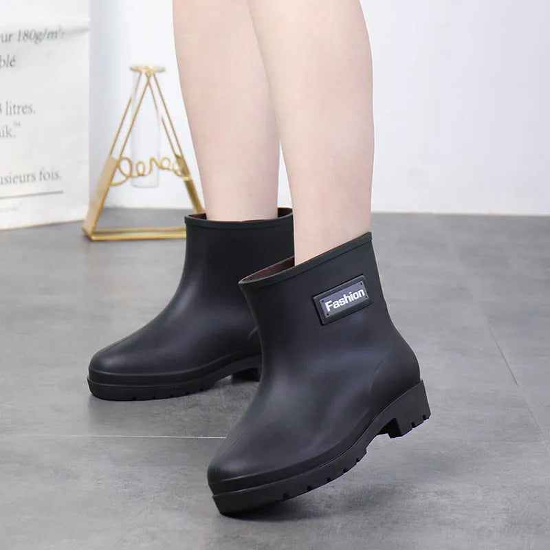 Women's mid-calf PVC rain boots in black with low heel, shown in short tube design