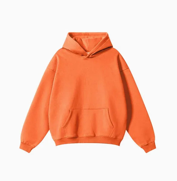 Man wearing a loose grey cotton terry hooded sweater with drop-shoulder sleeves.