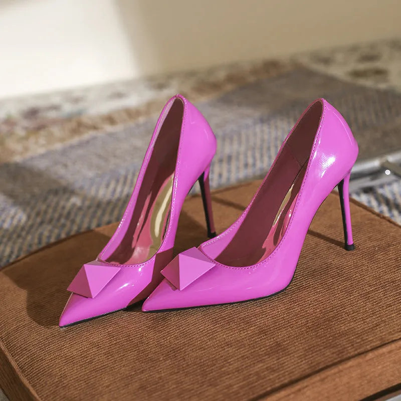 Pink women's pointed toe stiletto high heels with a buckle fastening on a patent leather upper.