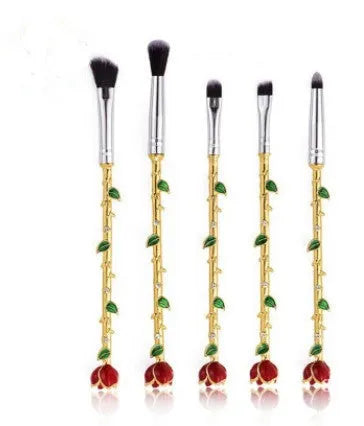 Beauty and the Beast makeup brush set with golden handles and synthetic bristles displayed on a surface