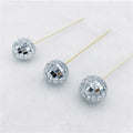Small glass mirror disco ball on a wooden stick used as a cake decoration