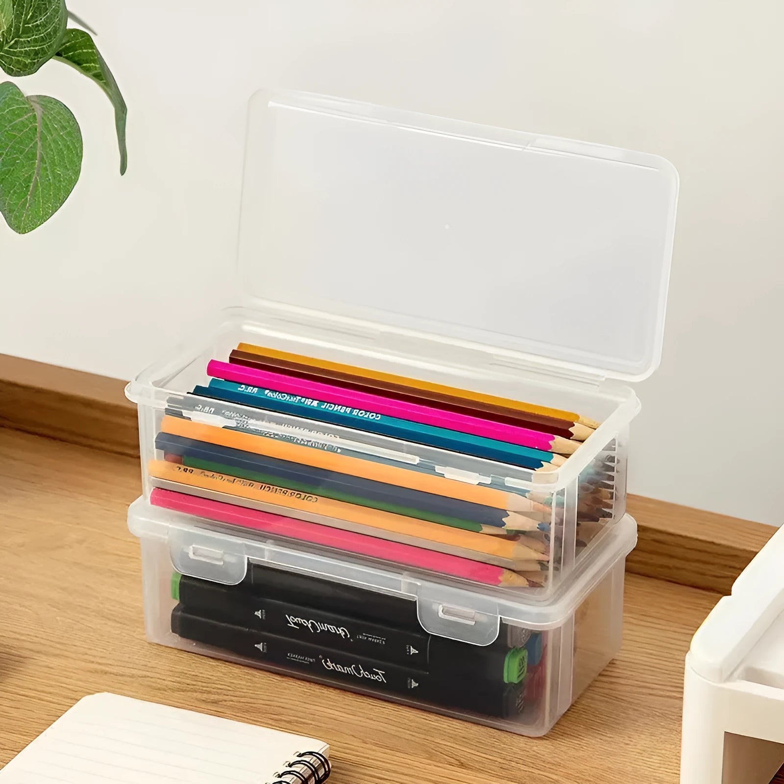 Clear plastic pencil storage box showing coloured pencils and drawing tools inside.