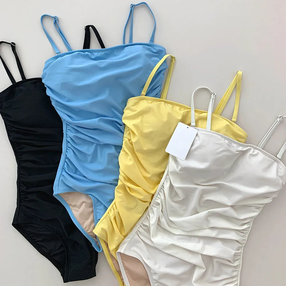 Sling style belly pleated one-piece swimsuit in solid color nylon and spandex blend for spring bathing