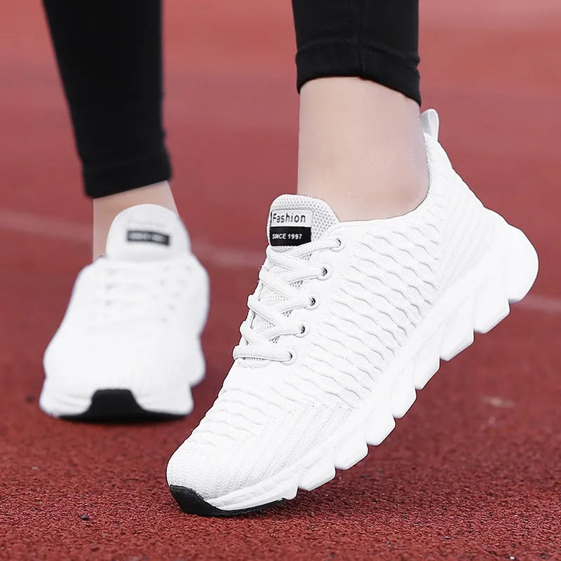 Women's black running shoes with a fly weave upper and a durable outsole on a track.