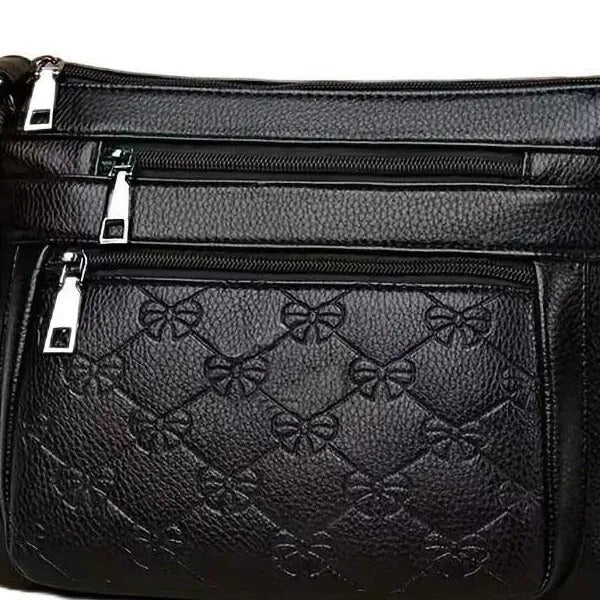 Black women's crossbody bag with butterfly embossed pattern and adjustable shoulder strap.