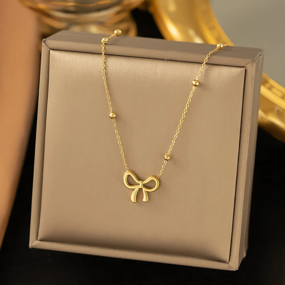 Gold electroplated bow pendant necklace with titanium steel cross chain, adjustable length