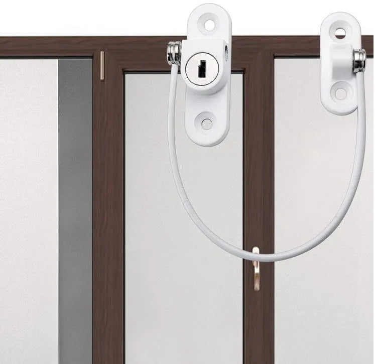 White window security chain lock with steel cable and adhesive base on a window frame