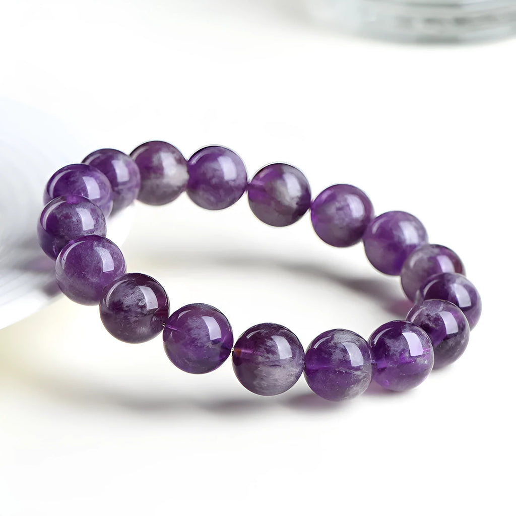 Natural feather amethyst purple crystal bracelet with geometric beads and Ruyi symbol on a white background.