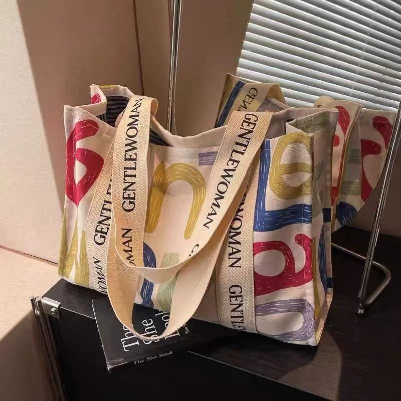 Large canvas tote bag with printed design showing black letters, available in multiple pattern options