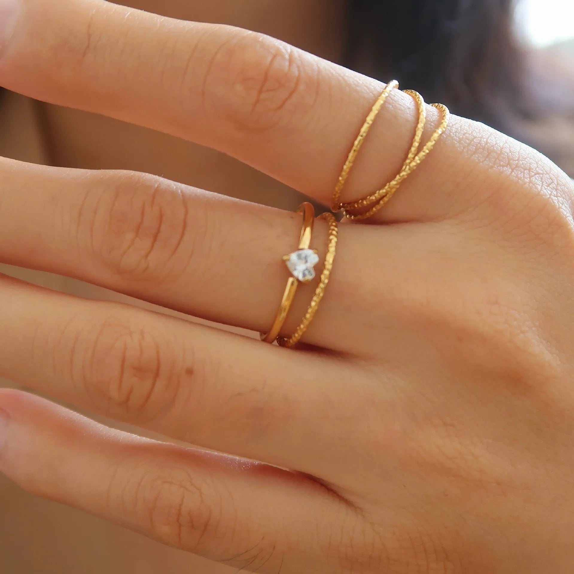 A golden stainless steel ring in a heart shape, shown next to an oval version, on a plain background.