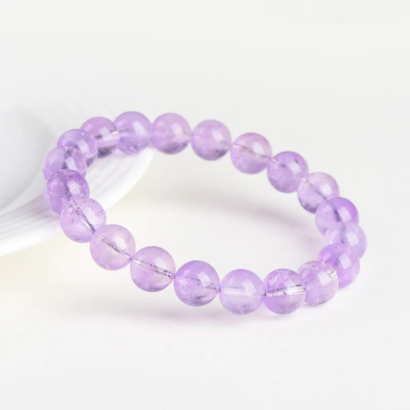 Lavender round amethyst bead bracelet with water ripple design on a wrist.
