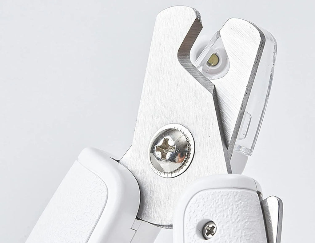 White pet nail clippers with LED light, transparent anti-splash guard, and leather-like handle on a table