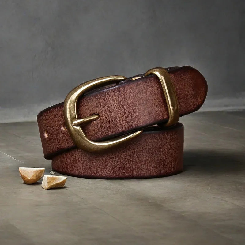 Men's brown leather belt with copper pin buckle on a pair of jeans.