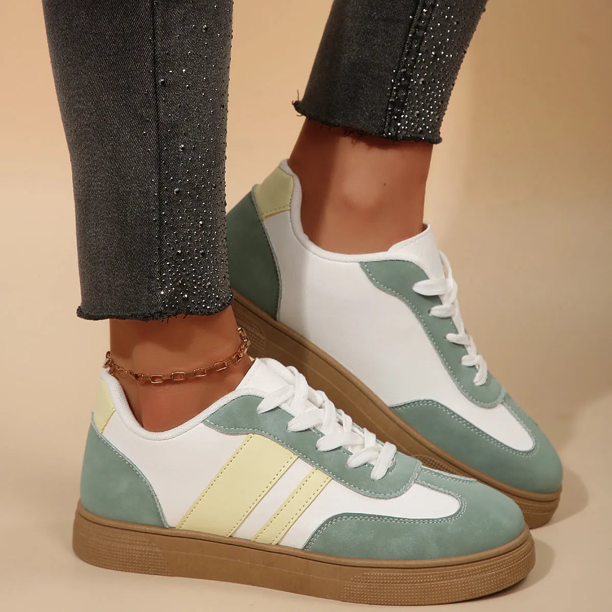 Green women's retro sports shoes with white cross-strap detail and leather stitching on a low rubber sole.
