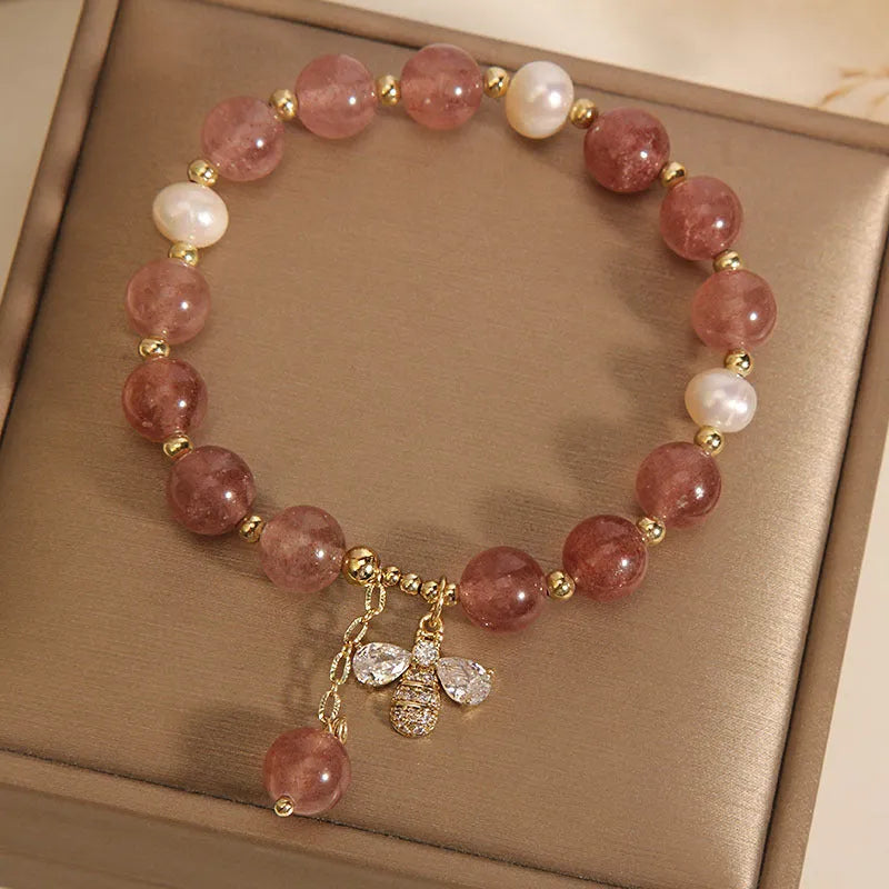 Women's bracelet with three freshwater pearls, a pink strawberry quartz charm, and sparkling zircon stones on an alloy chain.