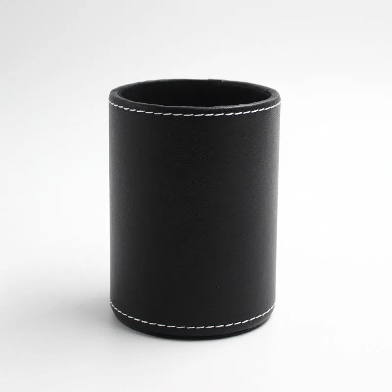 Round black leather pen holder container on desk with pens inside