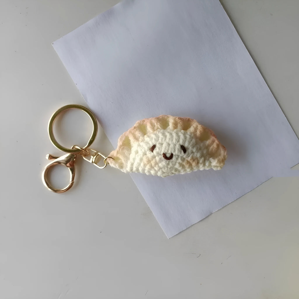 Handmade crochet dumpling pendant with Doudou Eye style and attached keychain on white background