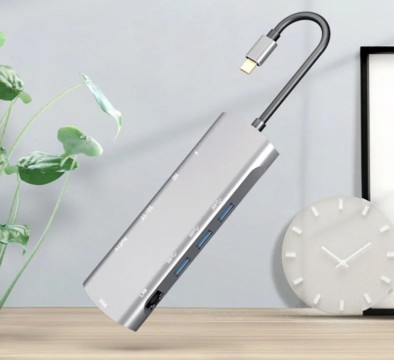 Grey aluminium USB-C docking station showing HDMI, VGA, USB 3.0, and USB-C PD charging ports.