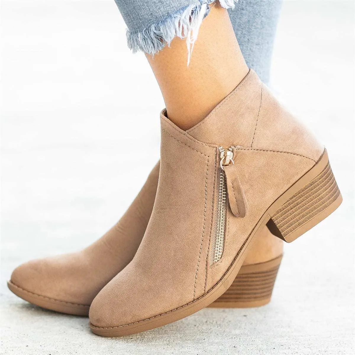 Women's beige suede ankle boots with a side zip and chunky block heel on a neutral background.