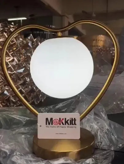 White heart shaped acrylic table lamp with LED light on a wooden surface