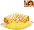Brown plaid plush cat tunnel bed with a zippered side and central mat, shown on a wooden floor.