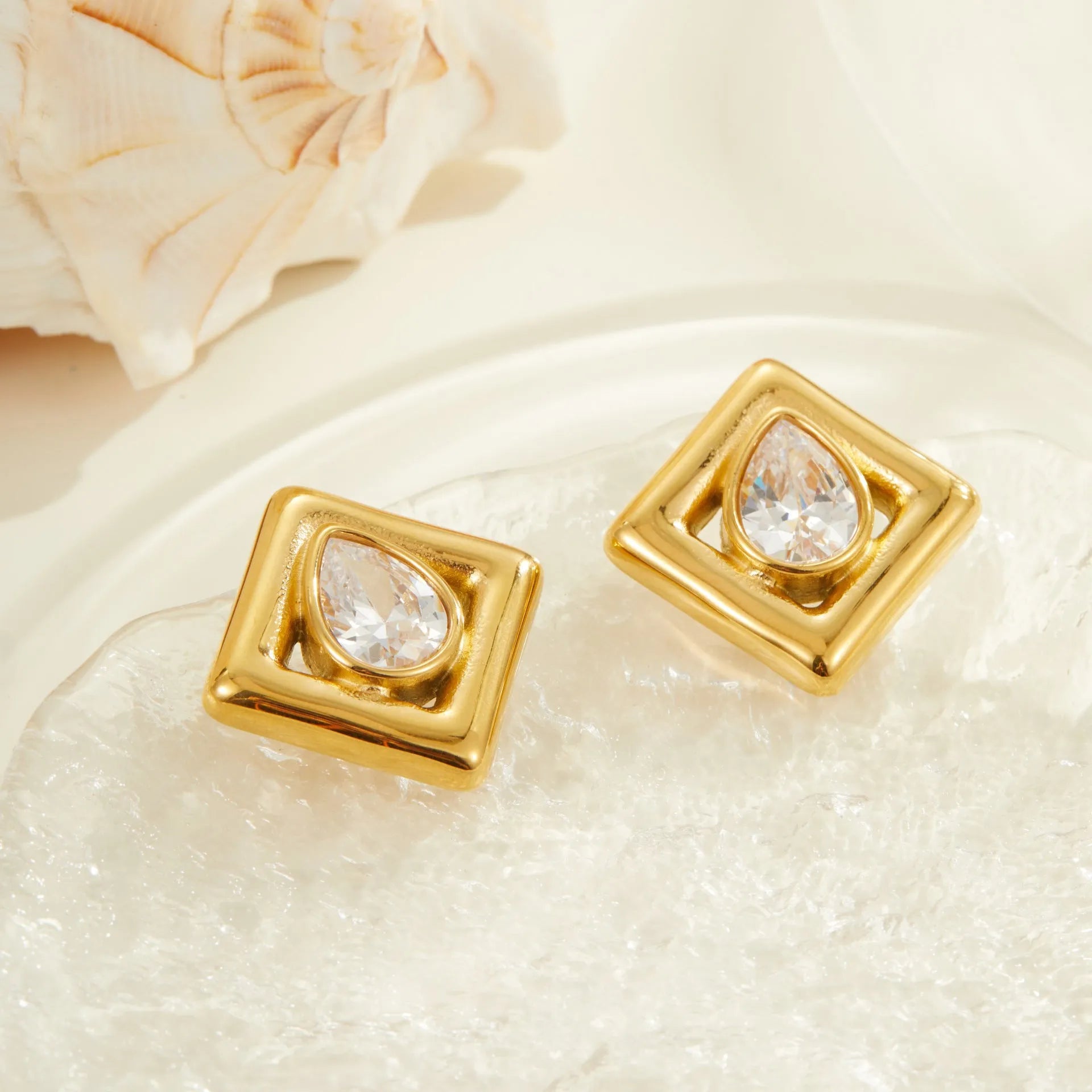Gold geometric water drop shaped stud earrings with a central zircon stone inlay.