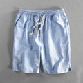 Man wearing black and white striped casual cotton shorts with a loose straight fit.