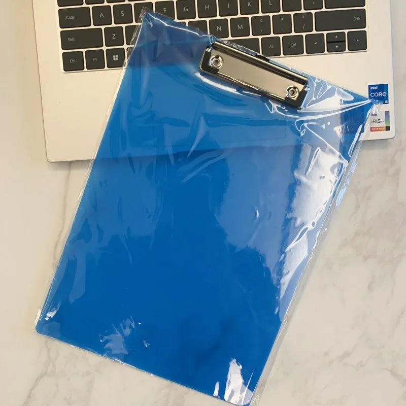 Transparent A4 plate holder with metal clip in blue, holding white paper, on a wooden desk.
