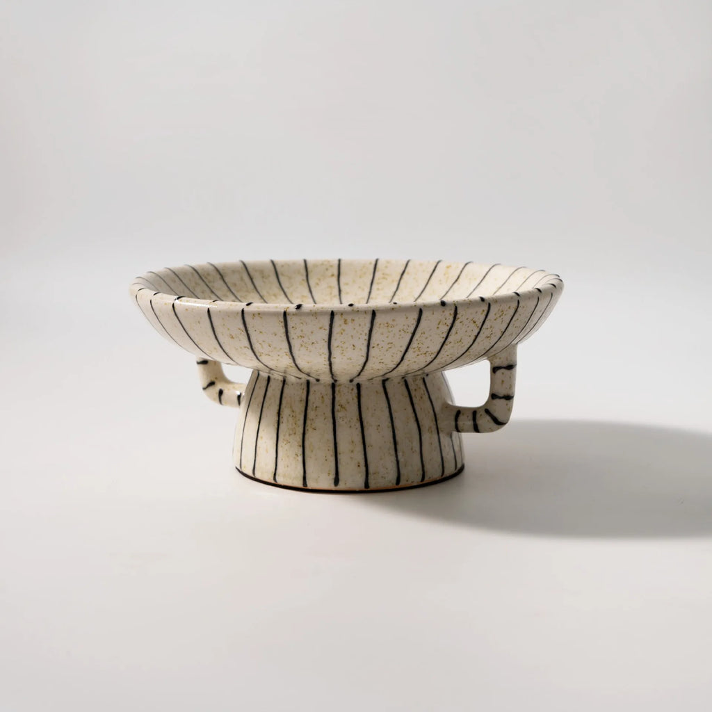 Black and white striped plastic resin dessert plate on a table.