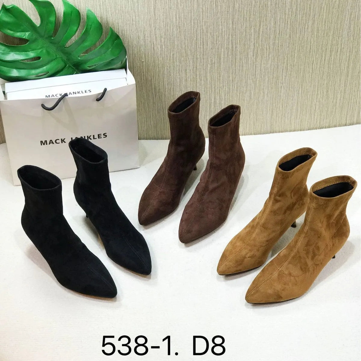 Black pointed toe stiletto ankle boots with a mid-calf sock on a plain background.