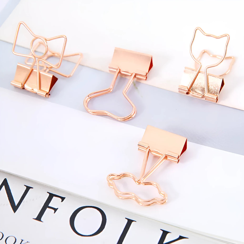 Small gold-plated metal stationery clip with a decorative bow charm design.