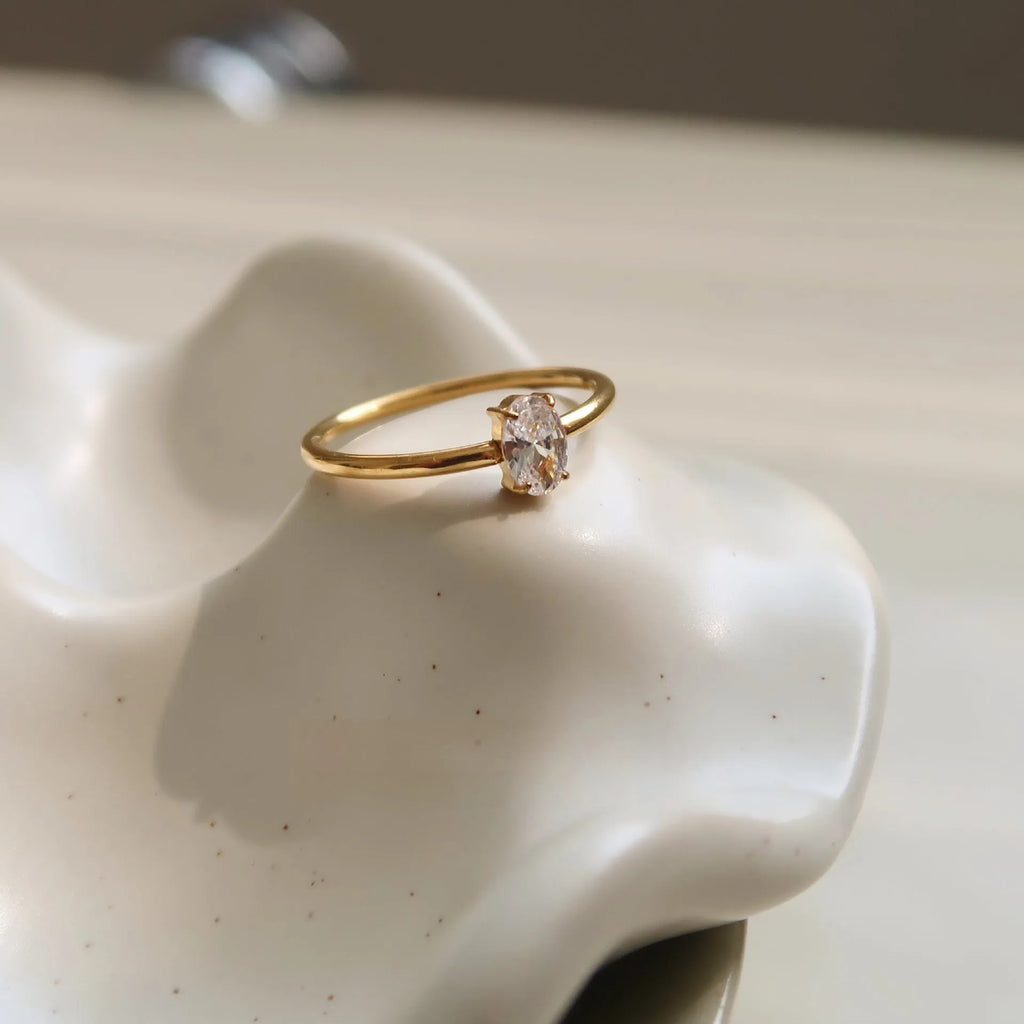 A golden stainless steel ring in a heart shape, shown next to an oval version, on a plain background.