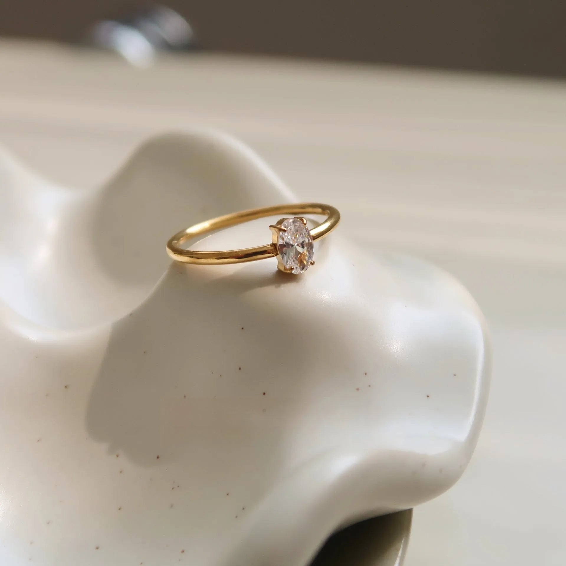 A golden stainless steel ring in a heart shape, shown next to an oval version, on a plain background.