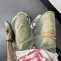 Men's blue loose-fit vintage denim shorts with yellow mud wash and ripped knee details.