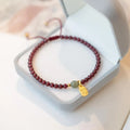 Hand-woven red rope bracelet with a strawberry quartz crystal charm on a wrist.