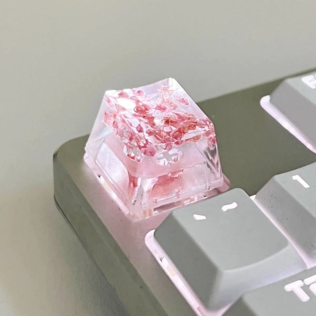 Transparent resin mechanical keyboard keycap with starry sky design in green, pink, red, violet colours.