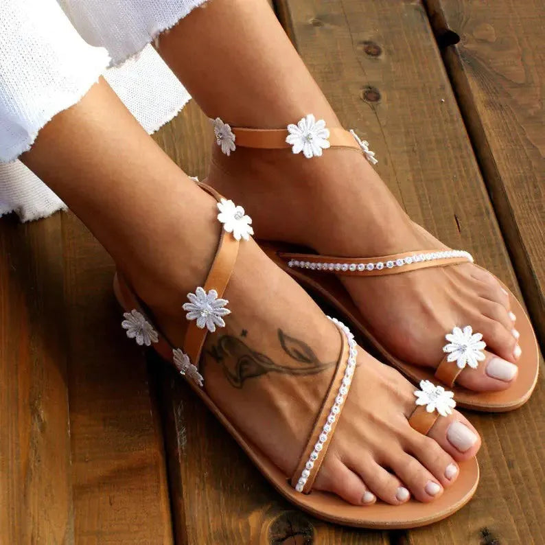 Brown women's flat sandals with flower detail and herringbone toe pattern on rubber sole.