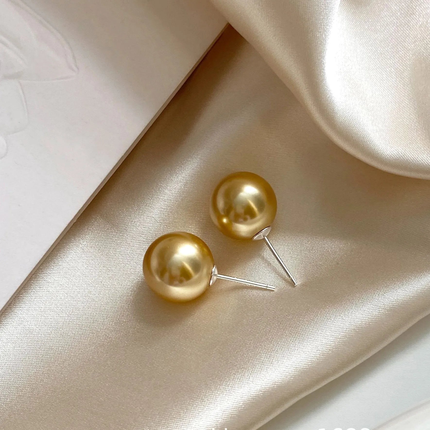 Large pearl stud earrings in geometric shape with eight awn star detail and pearl accents on silver background