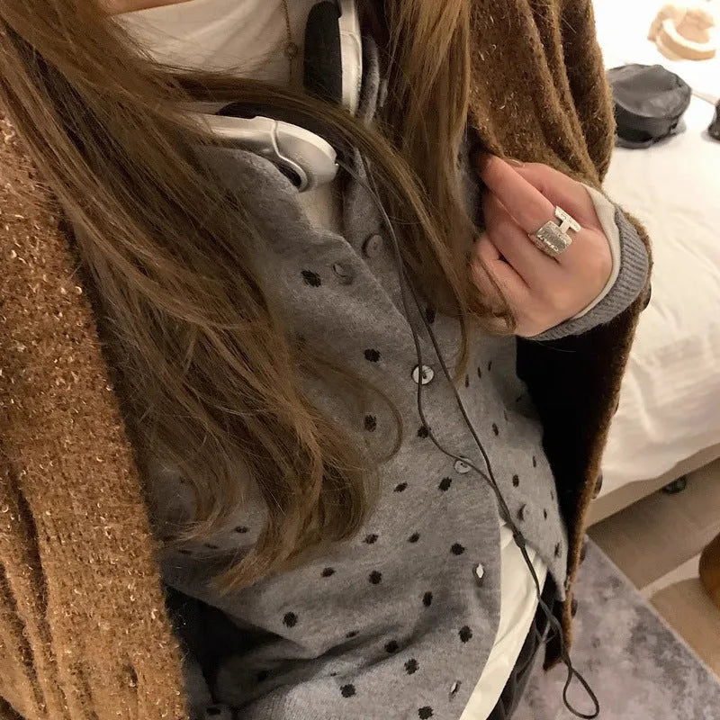 Women's grey loose-fit knitted cardigan with long sleeves on a hanger.