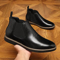 Men's black formal pointed-toe leather boots with a square heel and rubber sole on a plain background.