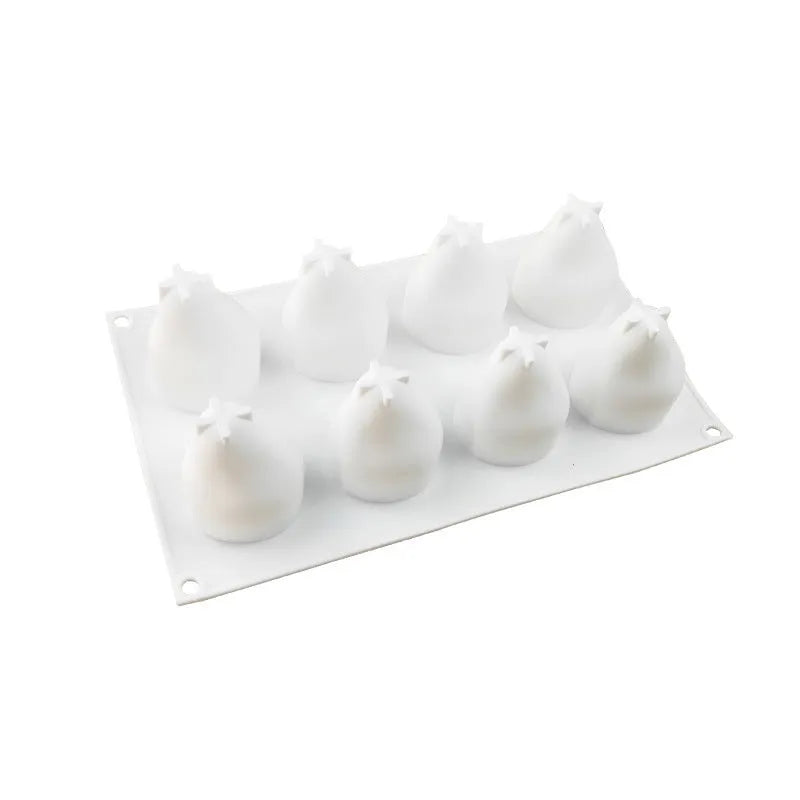 Set of six silicone baking moulds shaped like a pineapple, a pine cone, and a pear on a kitchen counter.