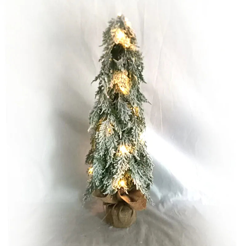 Small 24 inch artificial Christmas tree with lights and snow effect on a desktop
