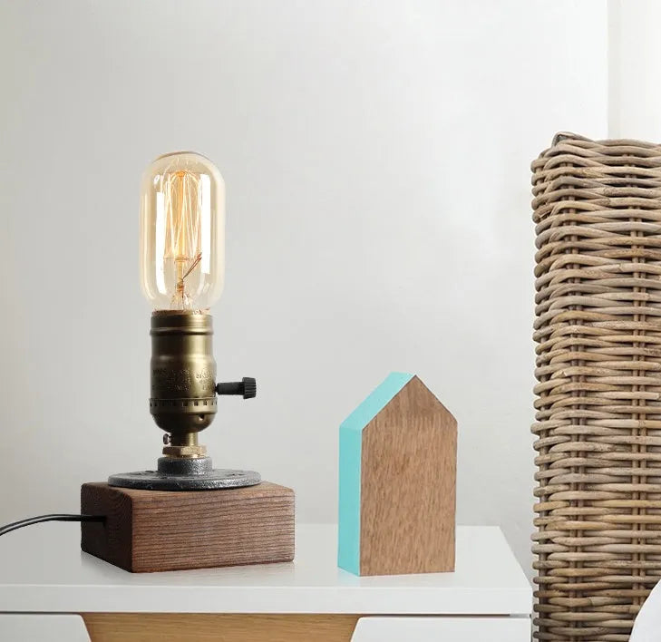 Industrial style wood and iron pipe table lamp with E26 socket on a wooden surface.