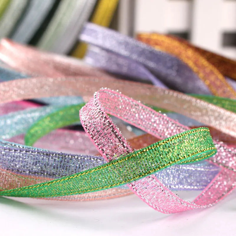 Roll of narrow gold polyester ribbon next to a wrapped gift box.