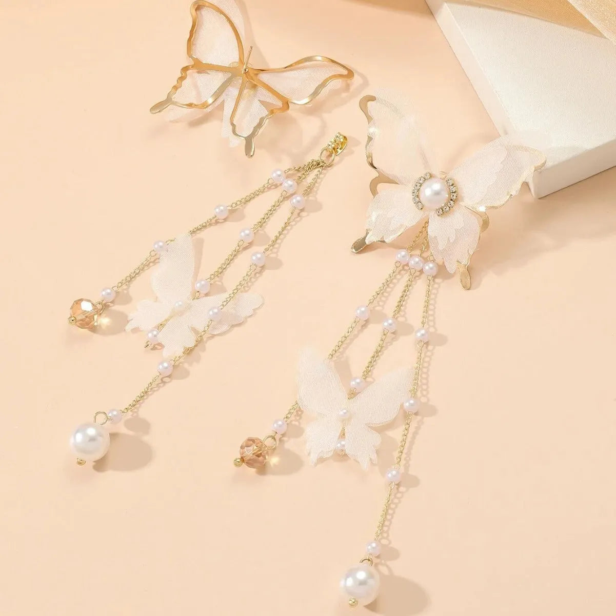 White butterfly-shaped earrings with lace patterns, pearl accents, rhinestone details, and tassel elements on copper alloy