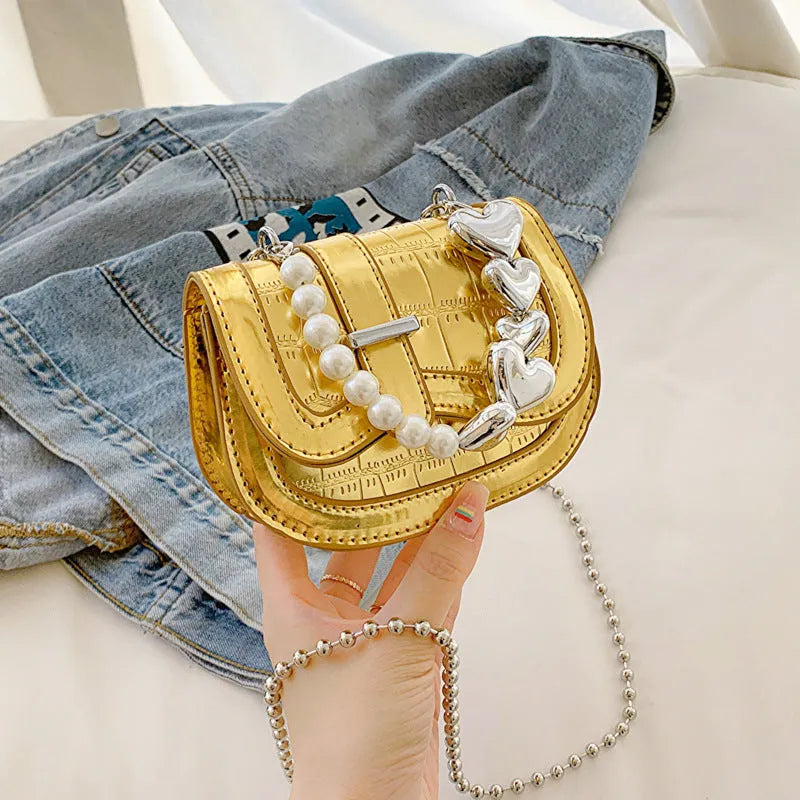 Silver laser pearl finish women's crossbody mini saddle tote bag with single shoulder strap.