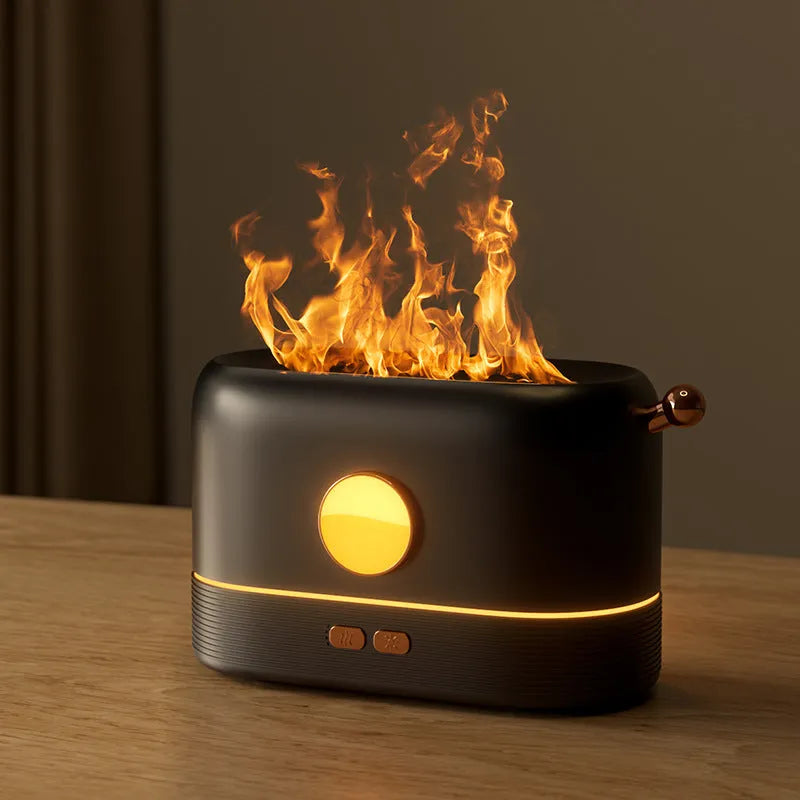 Black USB humidifier with flickering flame effect on a wooden desk next to a plant.