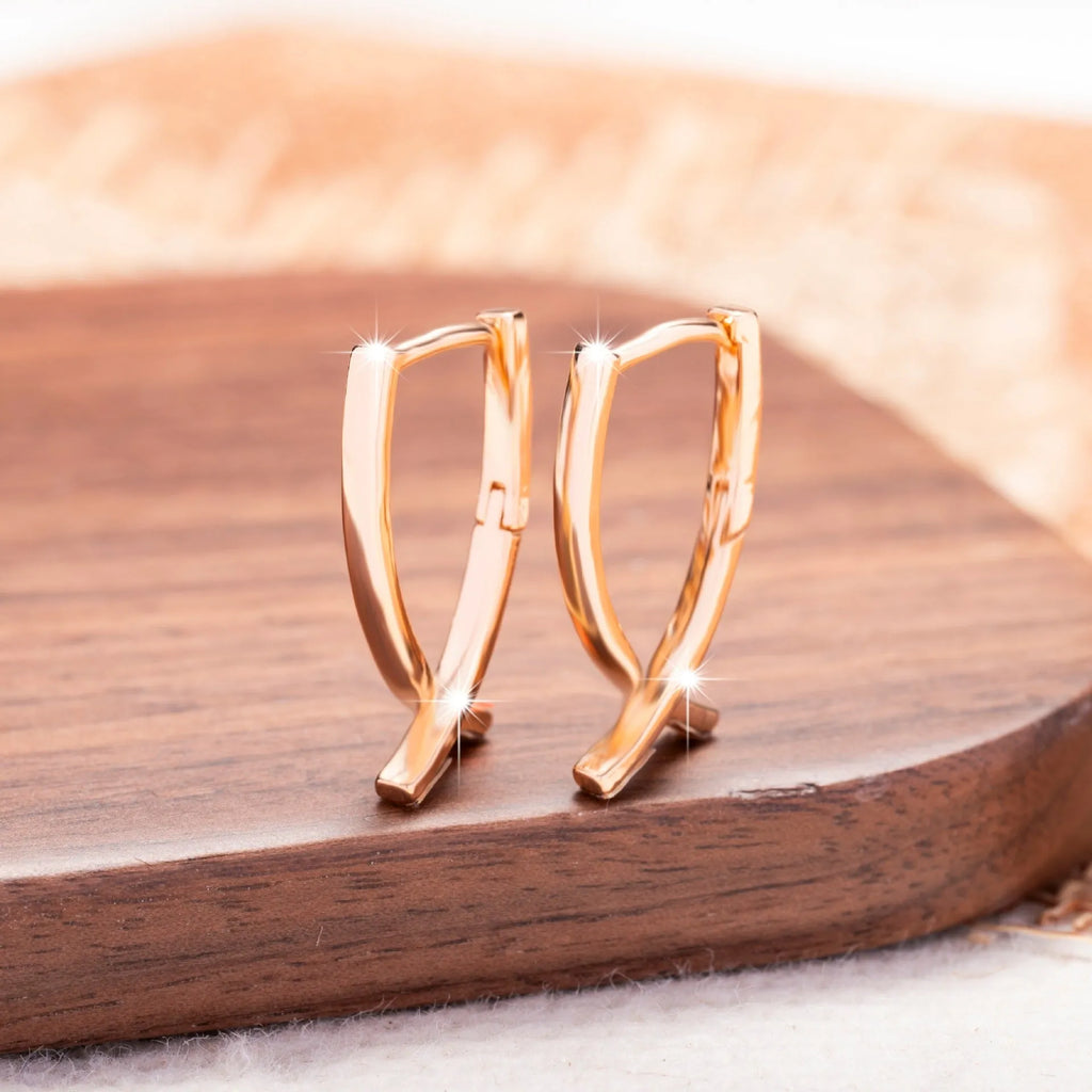 Rose gold cross shaped fashion earrings made from copper on a white background